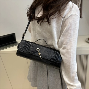 Elegant black crocodile pattern baguette handbag with silver buckle worn by a model