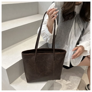 Dettaglio della borsa tote in pelle cerata marrone con trama e incisione del logo