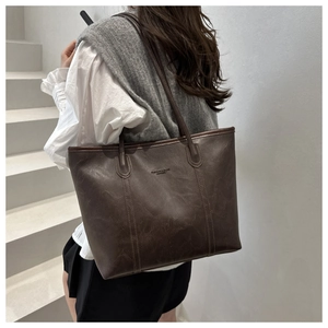 Dettaglio della borsa shopper in pelle marrone scuro con trama vintage e testo a sbalzo