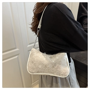 Detailed close-up of sparkling silver sequins and metal chain strap on the baguette bag