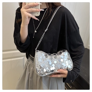 Bolso de hombro con lentejuelas plateadas en modelo con cadena metálica elegante
