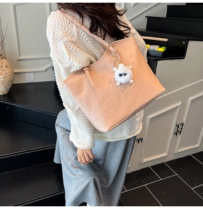 Pink tote bag detail with butterfly embossing and plush charm worn by model on stairs