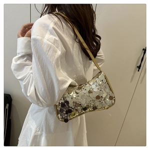 Gros plan d'un sac à bandoulière à paillettes argentées avec bordure en cuir doré