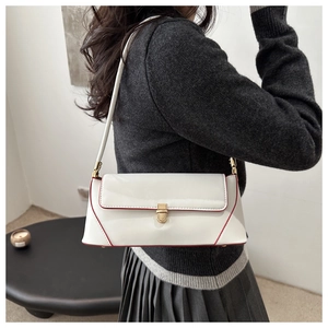 Detail of white patent leather baguette bag with red edge paint and gold buckle
