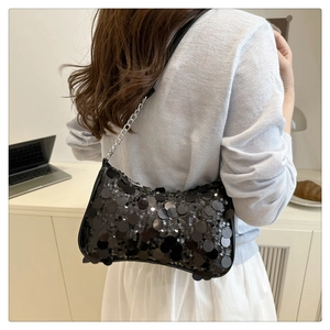 Detail of black sequin shoulder bag showing shimmering texture and silver chain strap