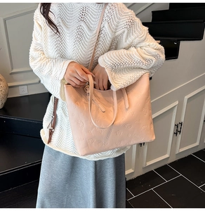 Detail of a dusty pink embossed tote bag showing 3D floral patterns and leather texture