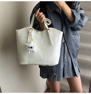 Detail of white embossed tote bag with floral patterns and a cute plush puppy charm