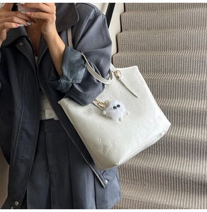 White tote bag detail showing 3D floral and bear embossing with soft plush pendant