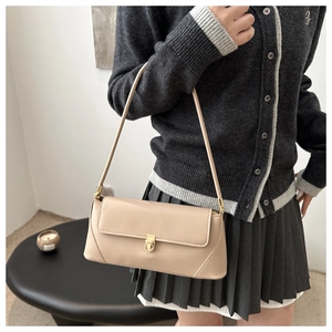 Detail view of a beige minimalist baguette bag with a premium golden lock on the front