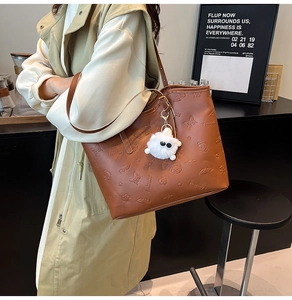 Detailed view of brown leather tote with floral embossing and plush cat charm
