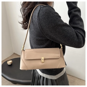 Detail of a chic beige baguette shoulder bag with gold metal buckle on a model