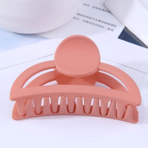Gros plan sur la pince à cheveux rose pêche mate avec design géométrique ajouré