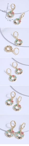 Detail view of gold butterfly evil eye earrings with colorful enamel and zircon stones