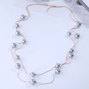 Detail of double-layer golden long necklace featuring grey faux pearls and lobster clasp