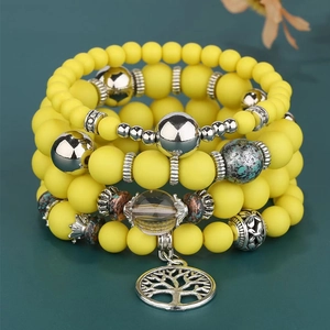Detail eines mehrlagigen mattgelben Perlenarmbands mit Lebensbaum-Silberanhänger