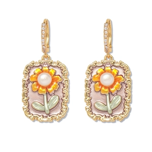 Détail de boucles d'oreilles vintage dorées avec fleur orange et perle d'eau douce naturelle