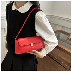 Close-up of a bright red retro underarm bag with a gold metal push-lock on a model