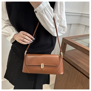 Close-up of caramel brown baguette bag with golden metal twist lock and leather texture