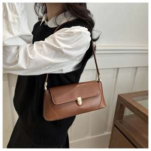Detail view of a vintage brown baguette bag with gold metal buckle and matte leather