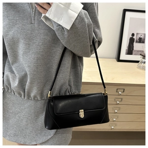 Close-up of black baguette shoulder bag with elegant gold buckle and leather texture