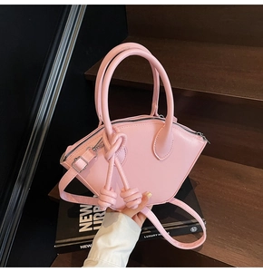 Détail d'un sac à main rose en forme d'éventail sur un escalier avec nœud et bandoulière