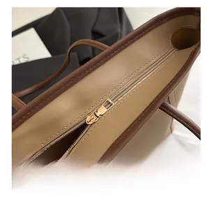 Close-up of khaki tote bag showing smooth gold metal zipper and premium leather texture