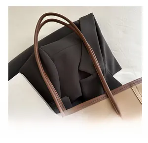 Detail of the brown leather handles and silver ball chain charm on a camel tote bag