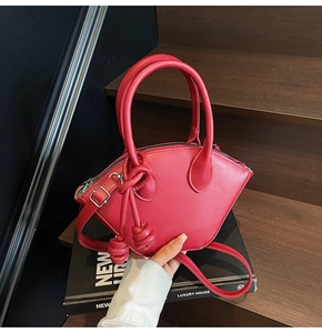 Vue détaillée du sac à main rouge en forme de croissant avec nœud décoratif et zip argenté
