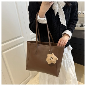Brown faux leather tote bag with stylish star pendant detail shown on a female model