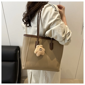 Detail of khaki tote bag with dark brown handles and cute plush star charm on the side