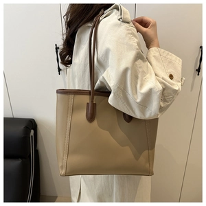 Close-up of contrast stitching and texture on a beige tote bag with dark brown handles