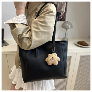 Detail of black matte leather tote bag with a brown plush star charm for commute