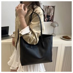 Minimalist black matte faux leather tote bag shown in a professional commuting setting