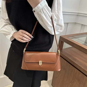 Vintage brown baguette bag with gold metal clasp on model for chic office commute