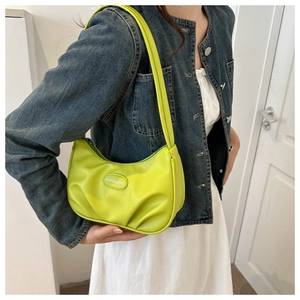 Gros plan du sac en croissant vert citron avec plis et étiquette sur veste en jean