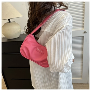 Détail du sac porté épaule plissé rose avec étiquette de marque sur cuir texturé