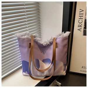 Detalle de bolso tote de lona morada con bordes de flecos y estampados florales abstractos