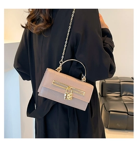 Detail der nude-rosa Handtasche mit Krokodilprägung, Goldgriff und Kette am Modell gezeigt