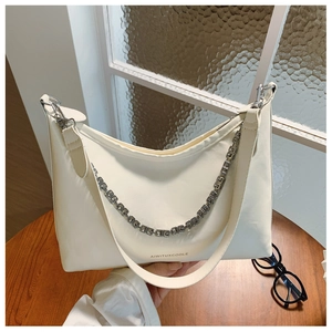Detail of cream PU leather crescent bag with silver G-chain and brand logo text