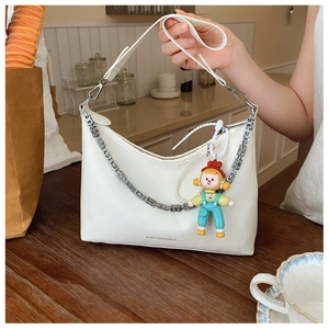 Close-up of white PU leather tote bag with brand logo, metal chain, and cute doll charm