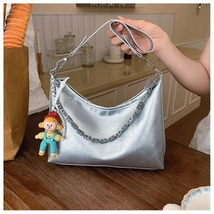 Detail of silver metallic hobo bag featuring geometric metal chain and a cute charm