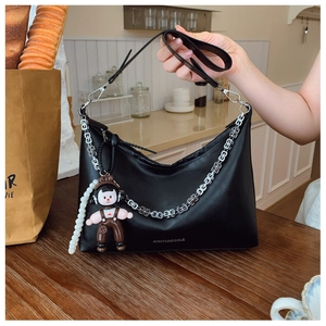 Detail of black matte leather hobo bag with silver chain and cute cartoon charm