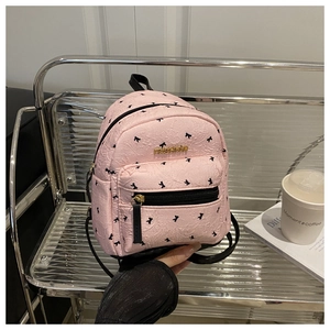Detail of pink mini backpack with wrinkle texture and black bow print and gold logo