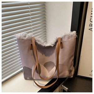 Detalle de bolso tote con estampado abstracto, bordes de flecos blancos y correas de cuero