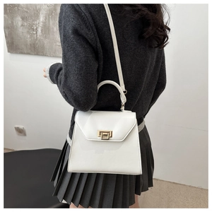 Détail d'un sac à bandoulière blanc en cuir porté par un mannequin en tenue moderne