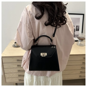 Vue détaillée du dos d'un sac à main noir chic avec fermoir doré et bandoulière réglable