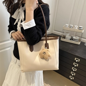 Classic cream tote bag with dark brown trim and cute plush bear charm for daily commute