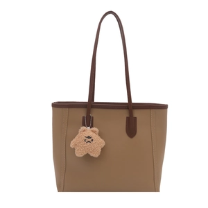 Brown contrast leather tote bag with long handles and a yellow star charm on white background