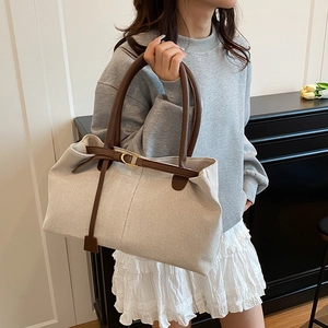 Vintage canvas tote bag with brown leather handles shown in a lifestyle casual setting