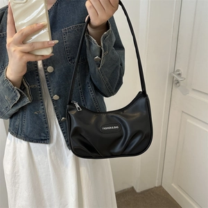 Sac hobo noir minimaliste en cuir PU plissé, porté à l'épaule sur une veste en jean bleu